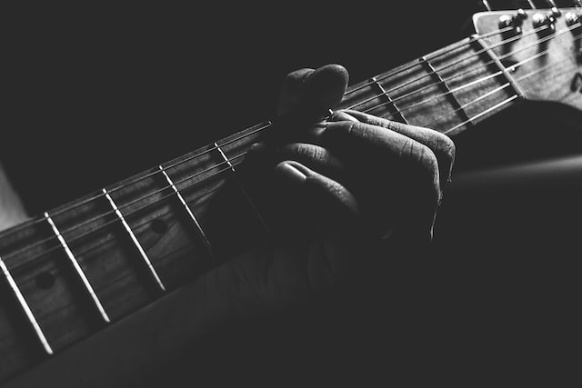 person holding guitar neck and strings