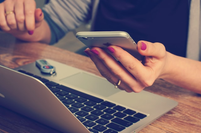 woman holding silver IPhone