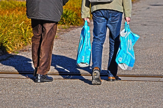 man carrying blue plastic bags