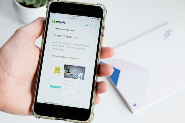 person holding phone with shopify