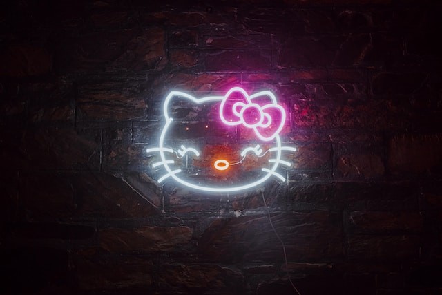 A neon hello kitty sign on a brick wall