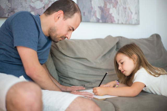 girl-drawing-on-a-paper-beside-a-man