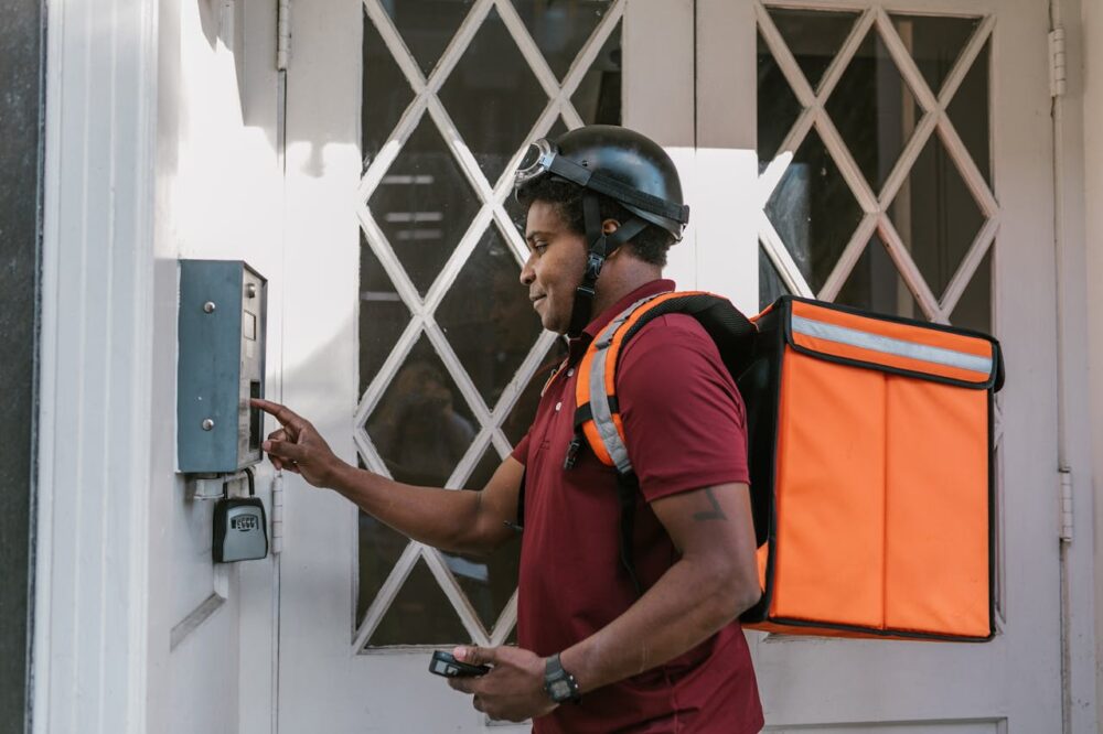 man-in-blue-and-orange-polo-shirt-wearing-black-helmet-holding-gray-metal-box