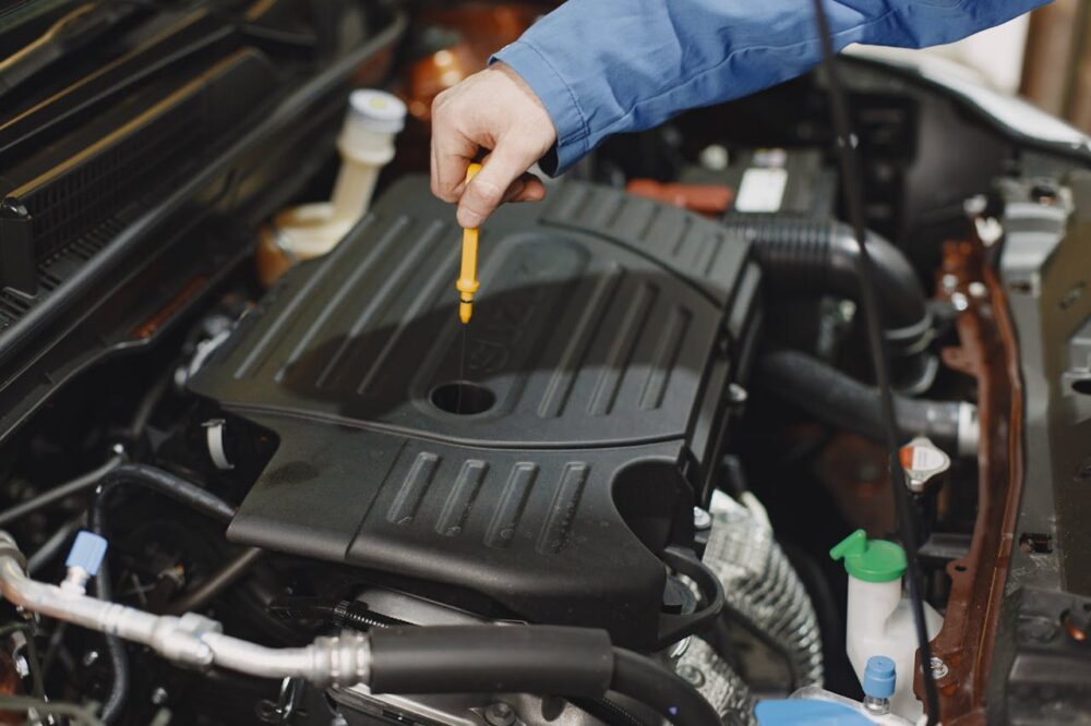 person-checking-the-oil-of-an-engine