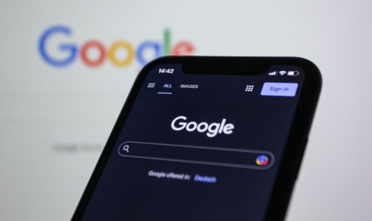 a-close-up-of-a-cell-phone-with-the-google-logo-in-the-background